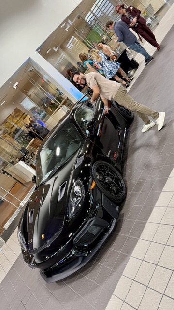 Posing with a black Porsche inside the Land Rover showroom